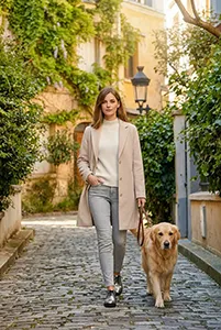 Femme marchant avec un chien dans une ruelle pavée végétalisée