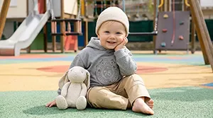 Bébé assis avec doudou dans une aire de jeux colorée