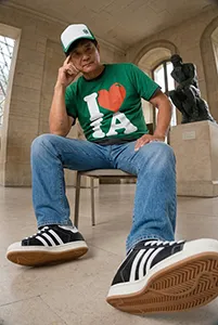 Homme assis dans un musée avec t-shirt vert et sneakers en vue basse