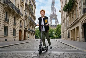 Enfant en trottinette devant la Tour Eiffel dans une rue parisienne