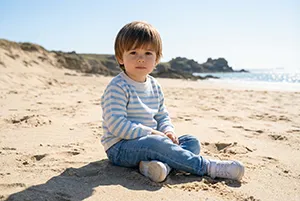 Jeune enfant assis sur une plage en lumière naturelle