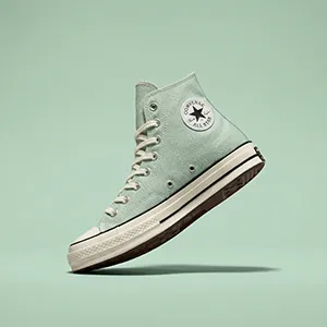 Chaussure type sneaker suspendue sur fond vert pastel